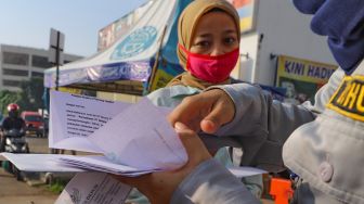 Petugas memeriksa surat tugas kantor para penumpang yang akan bekerja menggunakan transportasi Kereta Rel Listrik (KRL) di Stasiun Depok Baru, Depok, Jawa Barat, Jumat (15/5). [Suara.com/Alfian Winanto]