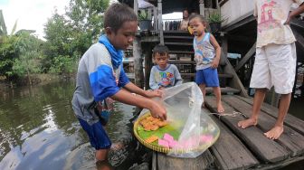 Bocah penjual kue (kiri) melayani pembeli dengan menerobos banjir luapan Sungai Batanghari yang menggenangi permukiman di Pelayangan, Jambi, Kamis (14/5).  ANTARA FOTO/Wahdi Septiawan
