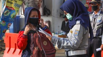 Petugas memeriksa surat tugas kantor para penumpang yang akan bekerja menggunakan transportasi Kereta Rel Listrik (KRL) di Stasiun Depok Baru, Depok, Jawa Barat, Jumat (15/5). [Suara.com/Alfian Winanto]