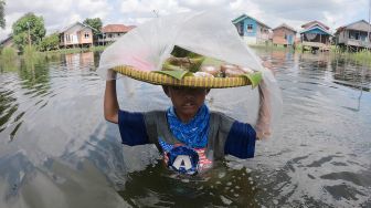 Perjuangan Seorang Bocah Terobos Banjir Demi Berjualan Kue