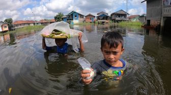 Dua bocah menerobos banjir luapan Sungai Batanghari yang menggenangi permukiman untuk berjualan di Pelayangan, Jambi, Kamis (14/5).  [ANTARA FOTO/Wahdi Septiawan]
