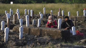 Peziarah berdoa di pemakaman khusus kasus COVID-19 di Tempat Pemakaman Umum (TPU) Keputih, Surabaya, Jawa Timur, Sabtu (16/5). [ANTARA FOTO/Zabur Karuru]