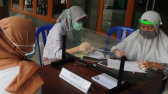 Petugas amil zakat dengan menggunakan pelindung wajah dan sarung tangan plastik melayani warga muslim yang membayar zakat fitrah di Masjid At Thoharoh, Ciputat, Tangerang Selatan, Banten, Jumat (15/5).  [ANTARA FOTO/Muhammad Iqbal]