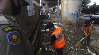 Warga yang terjaring razia penindakan pelanggaran aturan Pembatasan Sosial Berskala Besar (PSBB) oleh Tim Satgas Gugus Tugas COVID-19 menjalani hukuman dengan cara membersihkan sampah di kawasan Cilandak, Jakarta, Selasa (19/5). [Suara.com/Angga Budhiyanto]
