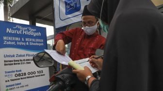 Warga mengisi formulir zakat fitrah di Masjid Nurul Hidayah, Tanah Kusir, Jakarta Selatan, Rabu (20/5). [Suara.com/Alfian Winanto]