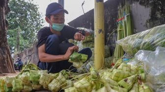 Pedagang mengikat satu beberapa kulit ketupat di Pasar Palmerah, Jakarta Pusat, Kamis (21/5). [Suara.com/Alfian Winanto]
