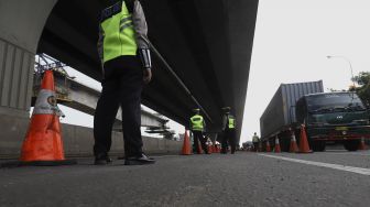 Petugas Kepolisian berjaga di Pos Penyekatan Jalur Mudik di Gerbang Tol Cikarang Barat, Kabupaten Bekasi, Jawa Barat, Rabu (20/5).  [Suara.com/Angga Budhiyanto]