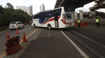 Petugas Kepolisian mengarahkan kendaraan untuk keluar dari Tol Jakarta-Cikampek, Cikarang Barat, Kabupaten Bekasi, Jawa Barat, Rabu (20/5). [Suara.com/Angga Budhiyanto]  