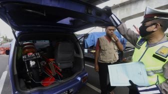 Petugas Kepolisian mengarahkan kendaraan untuk keluar dari Tol Jakarta-Cikampek, Cikarang Barat, Kabupaten Bekasi, Jawa Barat, Rabu (20/5). [Suara.com/Angga Budhiyanto]  