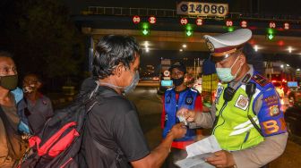 Petugas kepolisian memeriksa dokumen milik calon pemudik yang terjaring razia penyekatan di Pintu Tol Cikarang Barat, Bekasi, Jawa Barat, Kamis (21/5/2020). [ANTARA FOTO/Nova Wahyudi]