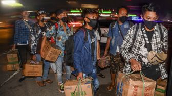 Calon pemudik yang terjaring razia penyekatan berjalan menaiki bus yang akan membawa mereka ke Terminal Pulogebang, Jakarta, di Pintu Tol Cikarang Barat, Bekasi, Jawa Barat, Kamis (21/5/2020).  [ANTARA FOTO/Nova Wahyudi]