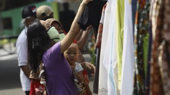 Warga memilih baju bekas layak pakai hasil sumbangan di RT 02 RW 04 Kelurahan Jati Padang, Jakarta, Jumat (22/5).  [Suara.com/Angga Budhiyanto]