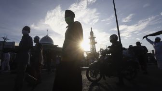 Umat Islam bergegas meninggalkan Masjid Jami An-Nur usai melaksanakan shalat Idul Fitri 1 Syawal 1441 Hijriah secara berjamaah di dalam mobilnya di ruas Jalan Jenderal Sudirman, Kranji, Bekasi, Jawa Barat, Minggu (24/5). [Suara.com/Angga Budhiyanto]  