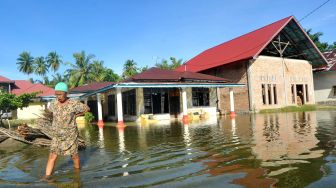 Warga berjalan di depan rumahnya yang terendam banjir rob di Tiram Ulakan, Kabupaten Padangpariaman, Sumatera Barat, Senin (25/5).  [ANTARA FOTO/Iggoy el Fitra]