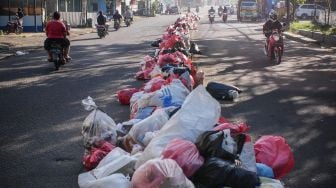 Pengendara melintas di dekat sampah yang menumpuk di pembatas jalan di Ciledug, Tangerang, Banten, Senin (25/5). [ANTARA FOTO/Rivan Awal Lingga]