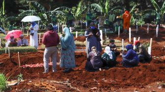 Keluarga berdoa di makam khusus korban Covid-19 di TPU  Pondok Ranggon, Jakarta Timur, Senin (25/5). [Suara.com/Alfian Winanto]