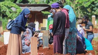 Keluarga berdoa di makam khusus korban Covid-19 di TPU  Pondok Ranggon, Jakarta Timur, Senin (25/5). [Suara.com/Alfian Winanto]