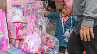 Seorang anak memilih mainan di Pasar Gembrong, Jakarta Timur, Selasa (26/5). [Suara.com/Alfian Winanto]
