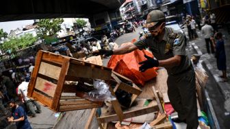 Anggota Satpol PP mengangkut barang-barang milik pedagang yang berjualan di kolong jembatan layang Pasar Pagi Asemka, Jakarta Barat, Rabu (27/5).   [ANTARA FOTO/Sigid Kurniawan]