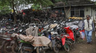 Petugas melintas diantara bangkai sepeda motor di tempat penampungan Teluk Pucung, Bekasi, Jawa Barat, Rabu (27/5). [Suara.com/Alfian Winanto]