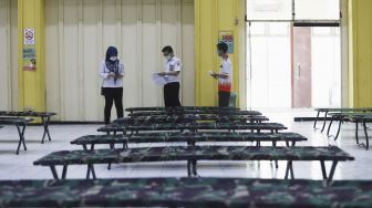 Petugas memeriksa kelengkapan berkas seorang penumpang di dalam Gedung Auditorium Gelanggang Remaja Gambir, Jakarta, Rabu (27/5). [Suara.com/Angga Budhiyanto]