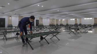 Petugas merapikan tempat tidur di ruang isolasi Masjid KH Hasyim Asy'ari, Cengkareng, Jakarta Barat, Kamis (28/5). [Suara.com/Alfian Winanto]