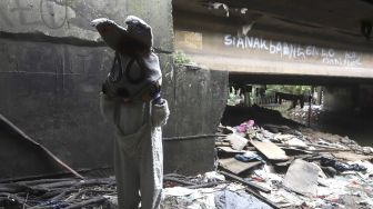 Selvi (20) mengenakan kostum badut kelinci bersiap mengamen di jembatan di kawasan Cibubur, Jakarta, Kamis (28/5). [Suara.com/Angga Budhiyanto]