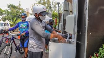 Warga diwajibkan mencuci tangan saat memasuki Kompleks Olahraga Gelora Bung Karno, Jakarta Pusat, Minggu (31/5). [Suara.com/Alfian Winanto]