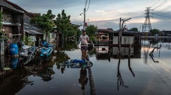 Seorang warga berdiri di tengah banjir rob yang merendam jalan desa di Desa Sriwulan, Sayung, Demak, Jawa Tengah, Senin (1/6/2020).  [ANTARA FOTO]