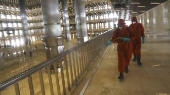 Petugas pemadam kebakaran melakukan penyemprotan cairan disinfektan di Masjid Istiqlal, Jakarta, Rabu (3/6). [Suara.com/Angga Budhiyanto]