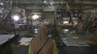 Pembeli berbelanja di lapak yang dipasangi tirai plastik di Pasar Bandeng, Kota Tangerang, Banten, Selasa (2/6). [Suara.com/Angga Budhiyanto]
