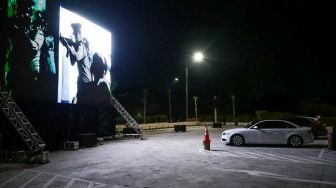 
Warga menonton film yang ditampilkan di layar drive-in cinema di area parkir Meikarta Cikarang, Jawa Barat, Selasa (2/6). [Anadolu/ Anton Raharjo] 