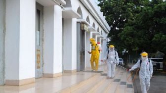 Petugas menyemprotkan cairan disinfektan area luar  Masjid Agung Al-Azhar, Jakarta Selatan, Rabu (3/6). [Suara.com/Alfian Winanto]