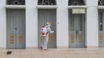 Petugas menyemprotkan cairan disinfektan area luar  Masjid Agung Al-Azhar, Jakarta Selatan, Rabu (3/6). [Suara.com/Alfian Winanto]