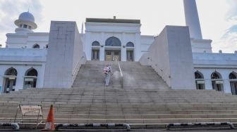 Petugas menyemprotkan cairan disinfektan area luar  Masjid Agung Al-Azhar, Jakarta Selatan, Rabu (3/6). [Suara.com/Alfian Winanto]