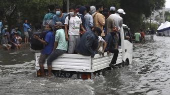 Warga naik mobil bak mencoba menerobos banjir rob di kawasan Pelabuhan Nizam Zachman, Muara Baru, Jakarta Utara, Jumat (5/6). . [Suara.com/Angga Budhiyanto]
