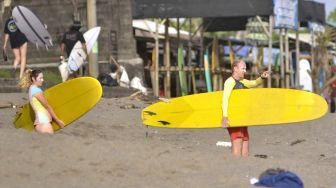 Turis membawa papan selancar di kawasan Pantai Canggu, Badung, Bali, Kamis (4/6/2020). [ANTARA FOTO/Fikri Yusuf]