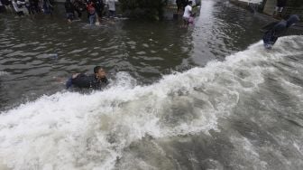 Warga berenang saat banjir rob di kawasan Pelabuhan Nizam Zachman, Muara Baru, Jakarta Utara, Jumat (5/6). . [Suara.com/Angga Budhiyanto]
