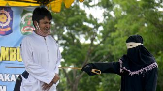 Seorang pria terpidana dalam kasus zina menjalani hukuman cambuk di Masjid Al Munawarah, Kota Jantho, Kabupaten Aceh Besar, Aceh, Jumat (5/6).   [ANTARA FOTO/Ampelsa]