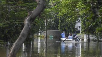 Warga menggunakan perahu untuk melintasi banjir rob di Kompleks Pantai Mutiara, Penjaringan, Jakarta, Minggu (7/6). [ANTARA FOTO/Hafidz Mubarak A]