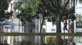 Warga melintas di Kompleks Pantai Mutiara yang tergenang banjir rob di Penjaringan, Jakarta, Minggu (7/6). [ANTARA FOTO/Hafidz Mubarak A]