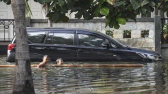 Dua anak bermain air saat banjir rob menggengangi Kompleks Pantai Mutiara, Penjaringan, Jakarta, Minggu (7/6). [ANTARA FOTO/Hafidz Mubarak A]