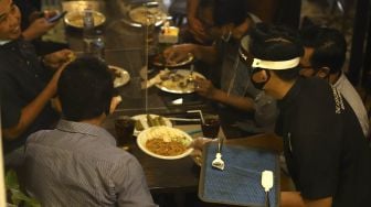 Seorang pelayan menggunakan alat pelindung wajah saat melayani pengunjung di The Atjeh Connection Resto and Coffee, Jakarta, Senin (8/6). [Suara.com/Angga Budhiyanto]