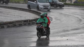 Ojek online menerobos hujan dengan membawa penumpang di Jalan Sudirman, Jakarta Pusat, Senin (8/6). [Suara.com/Alfian Winanto]