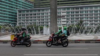 Ojek online membawa penumpang melintas di kawasan Bundaran Hotel Indonesia, Jakarta Pusat, Senin (8/6). [Suara.com/Alfian Winanto]
