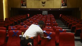 Petugas memasang tanda menjaga jarak fisik di ruang pemutaran film Perpustakaan Nasional Republik Indonesia, Jakarta, Rabu (10/6). [Suara.com/Angga Budhiyanto]