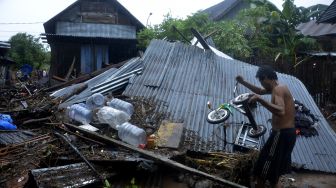 Seorang warga mengangkat sisa barangnya didekat rumah yang rusak terseret arus banjir bandang di Kecamatan Bissappu, Kabupaten Bantaeng, Sulawesi Selatan, Sabtu (13/6). [ANTARA FOTO/Abriawan Abhe]