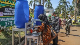 Pelayat mencuci tangan sebelum melayat kerumah duka mantan Kepala Staf TNI Angkatan Darat (KSAD) Letjen TNI Pramono Edhie Wibowo di Puri Cikeas, Bogor, Jawa Barat, Minggu (14/6). [Suara.com/Alfian Winanto]