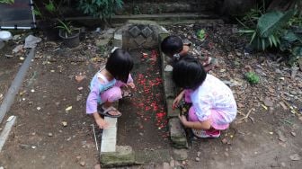 Anak - anak bermain di kuburan di Pisangan, Jakarta Timur, Selasa (16/5). [Suara.com/Alfian Winanto]