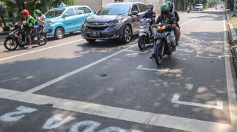 Pengendara motor berhenti pada garis pembatas antar pengendara di Jalan Hang Tuah Raya, Jakarta Selatan, Selasa, (16/6). [Suara.com/Alfian Winanto]